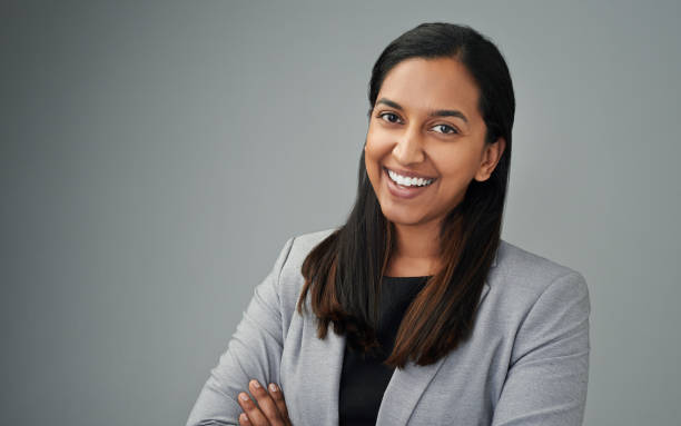 Studio Portrait Of A Young Businesswoman Standing Against A Grey Background